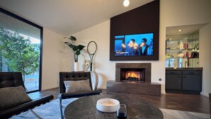 Una sala de estar moderna con chimenea, televisor y comedor.