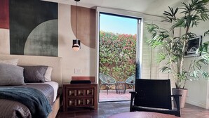 Un dormitorio con cama, mesita de noche y vistas a un jardín a través de una puerta corredera.