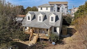 A two-story house with a porch, a staircase, and a sign indicating it's for sale.