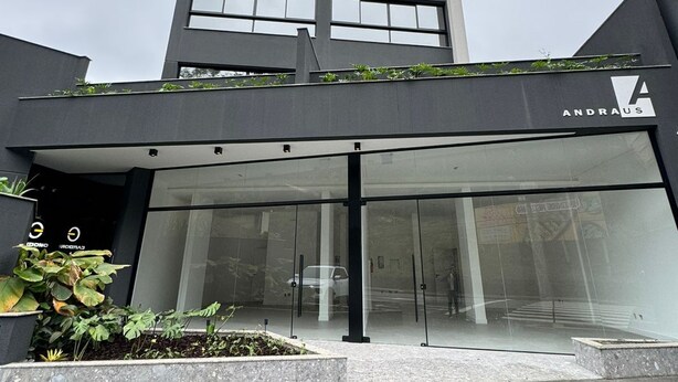 A modern building with a glass entrance and a sign reading "ANDRAUS". - Brand new loft next to Vila Germanica (Blumenau)