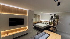 Een moderne slaapkamer met een bed, nachtkastje en een aan de muur bevestigde televisie.