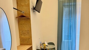 A small room with a tiled floor, a table with chairs, a TV mounted on the wall, and a window with curtains. - Palermo Central Rooms (Palermo)