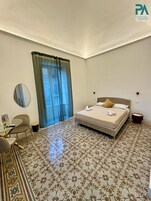Una habitación de hotel con una cama, un espejo redondo, una mesita pequeña y una silla.