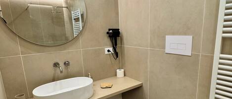 A modern bathroom with a round mirror, a sink, a bidet, and a toilet.
