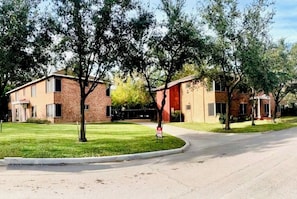 A residential area with brick buildings, a grassy lawn, and a street.