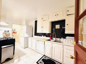 A kitchen with white cabinets, a black backsplash, a gas stove, and a refrigerator.