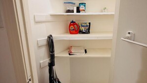 A narrow hallway with white walls and shelves containing cleaning supplies. - Private 2BR and 1BA Condo in Texas Medical Center Houston - Apartment 6710-1 (Houston)