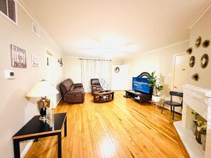 Un salon avec un canapé, une table basse, un téléviseur et une cheminée.