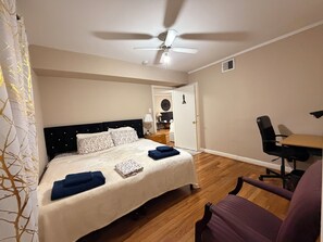 Un dormitorio con una cama, ventilador de techo, escritorio y una silla.
