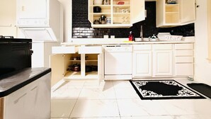 A compact kitchen with white cabinetry, a black backsplash, and a marble floor. - Private 2BR and 1BA Condo in Texas Medical Center Houston - Apartment 6710-1 (Houston)