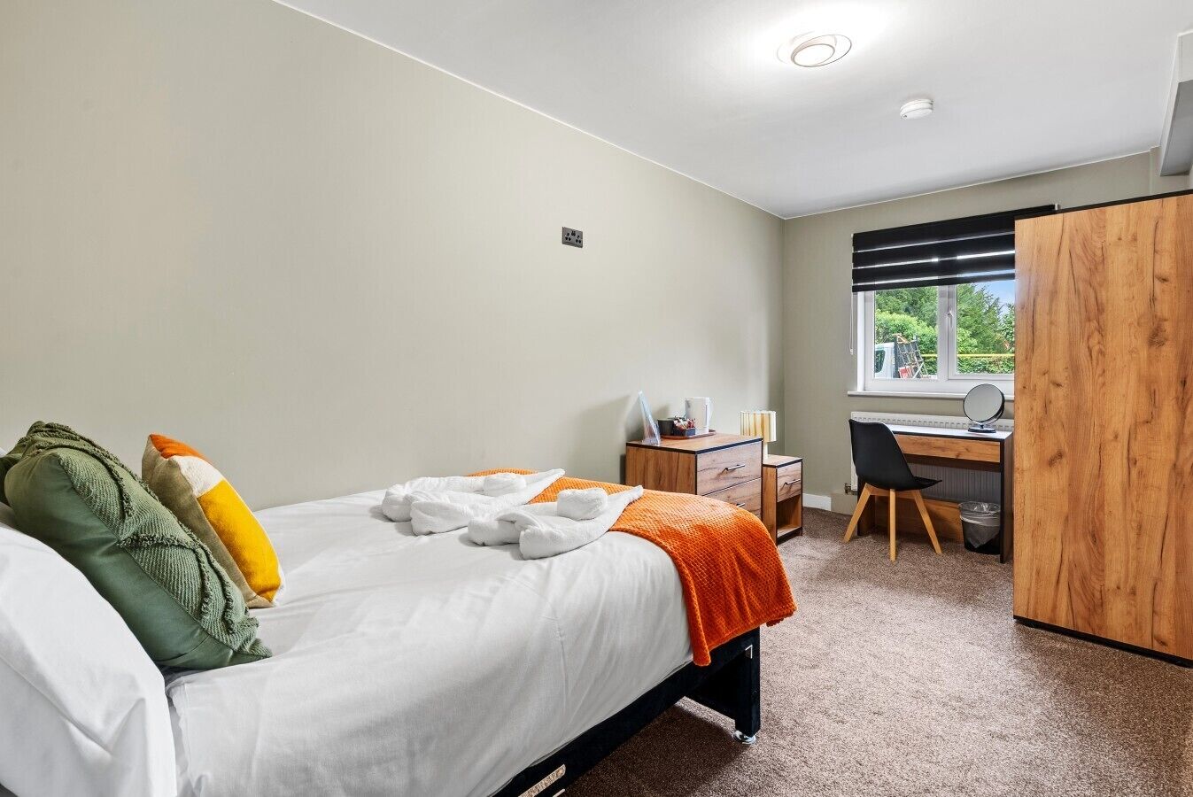 A bedroom with a bed, a desk, a chair, and a wardrobe.
