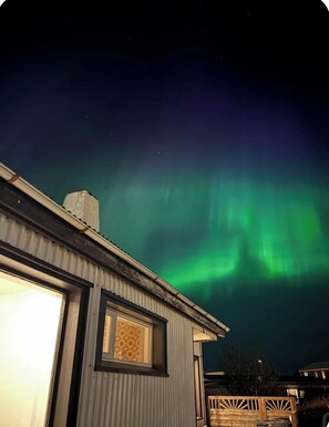 Une maison avec une fenêtre bien visible, d’où l’on peut admirer le ciel nocturne.