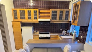 A modern kitchen with wooden cabinets, a central island, and a dining table with fluffy chairs. - 4-bedroom house in Höfn í Hornafirði (Höfn í Hornafirði)