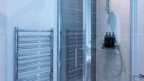 A modern bathroom with a glass shower enclosure, a chrome towel rack, and a glass showerhead. - Spacious Ancoats -pool-gym-free Parking (Manchester)