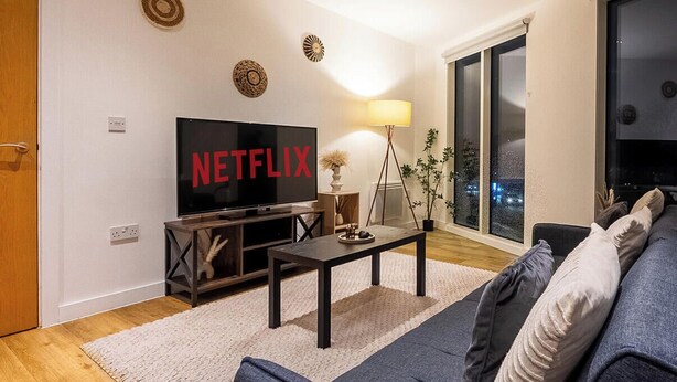 Ein Wohnzimmer mit einer Couch, einem Couchtisch, einem Fernseher und einer Lampe.
