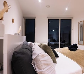 Un dormitorio moderno con una cama, un sofá y un ventanal grande.