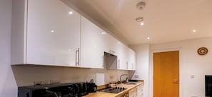 Una cocina moderna con armarios blancos, encimera de madera, horno empotrado y un lavabo.