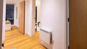 Ein Flur mit Holzboden, einem Heizkörper und einer Tür zu einem Schlafzimmer.