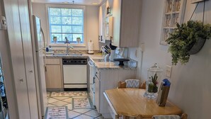 Una cocina con comedor, que incluye piso de baldosas, mesa de madera y armarios.