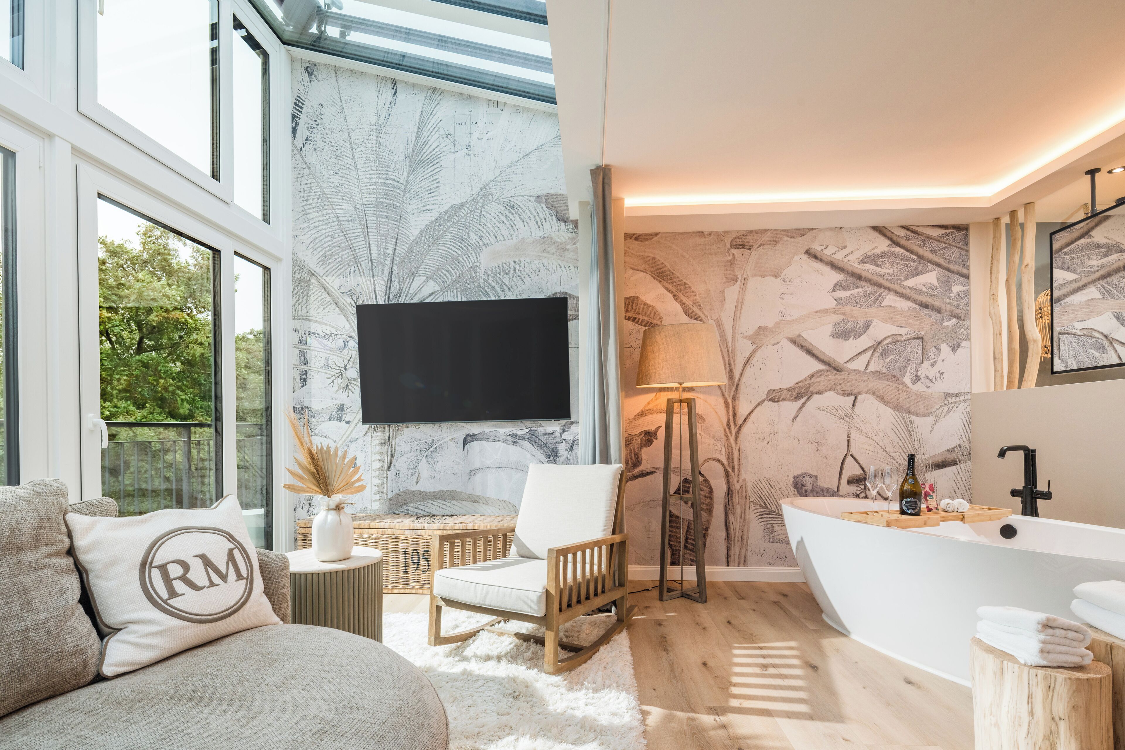 A modern bathroom with a freestanding bathtub, a large mirror, and a wall-mounted television.