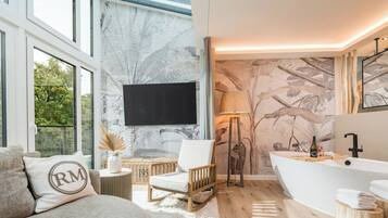 A modern bathroom with a freestanding bathtub, a large mirror, and a wall-mounted television.