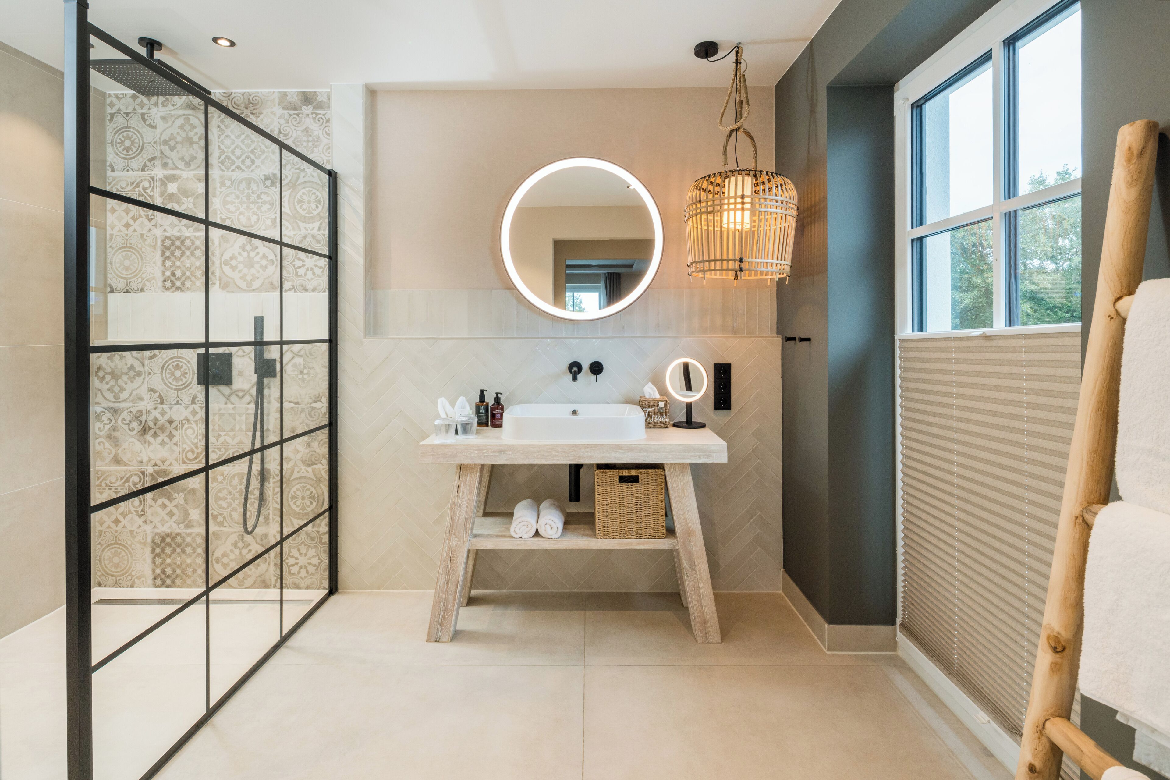 Een moderne badkamer met een grote spiegel, een houten wastafelmeubel en een douche met patroon betegelde wanden.