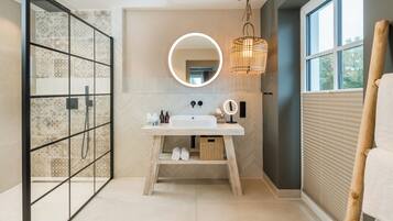 Een moderne badkamer met een grote spiegel, een houten wastafelmeubel en een douche met patroon betegelde wanden.