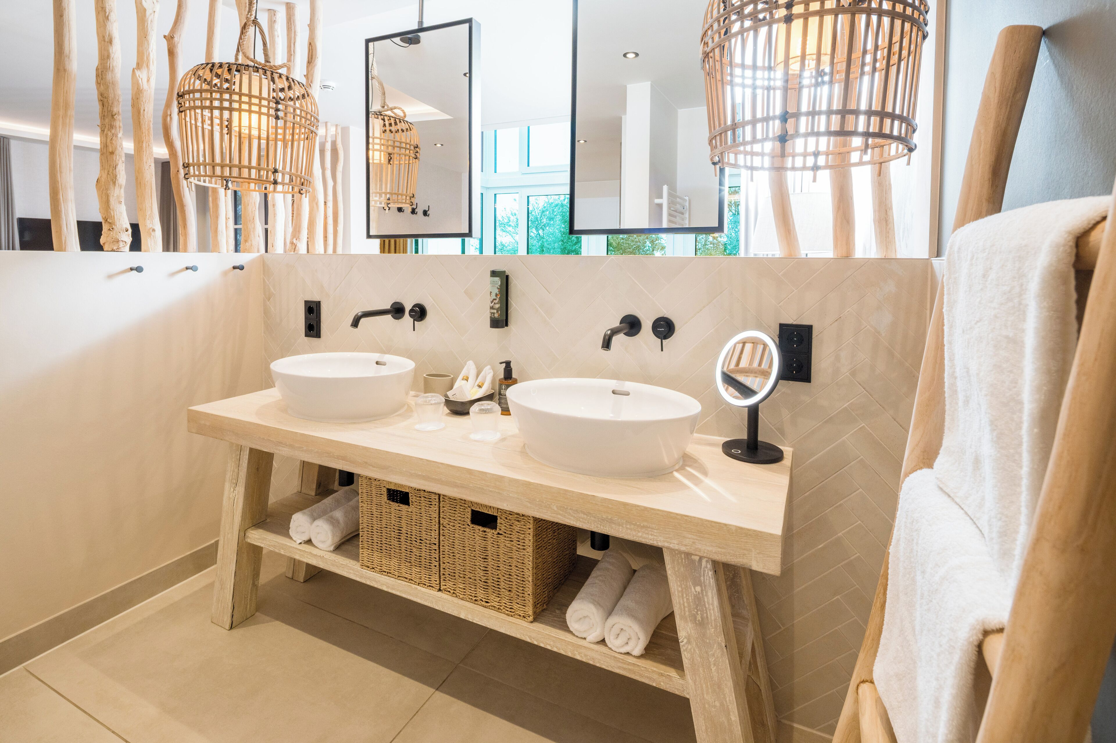 Ein modernes Badezimmer mit zwei Waschbecken, Korbwannen und einem großen Spiegel.