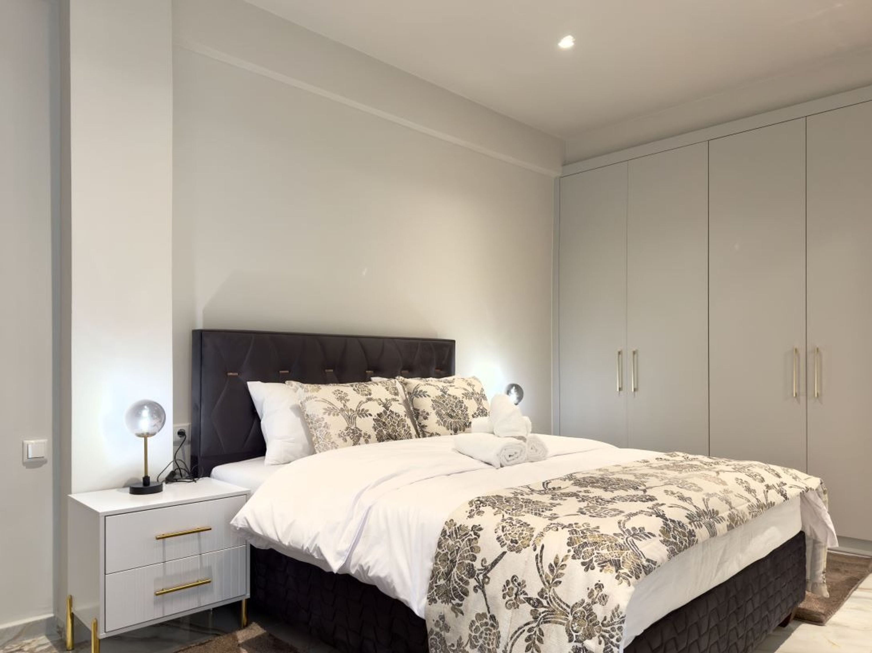 Ein modernes Schlafzimmer mit einem großen Bett, einem Nachttisch und einem Kleiderschrank.