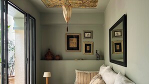 A room with a sofa, a wooden table with a lamp, a ceiling with a decorative pattern, and framed artwork on the walls. - Romantic Private Little Riad in Heart of Marrakech Medina (Marrakesh)