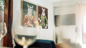 A dining area with a table set for two, a wine glass, and two framed artworks on the wall.