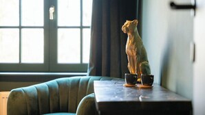 Une pièce avec un canapé, une table sur laquelle se trouve une statue, et une fenêtre avec des rideaux.