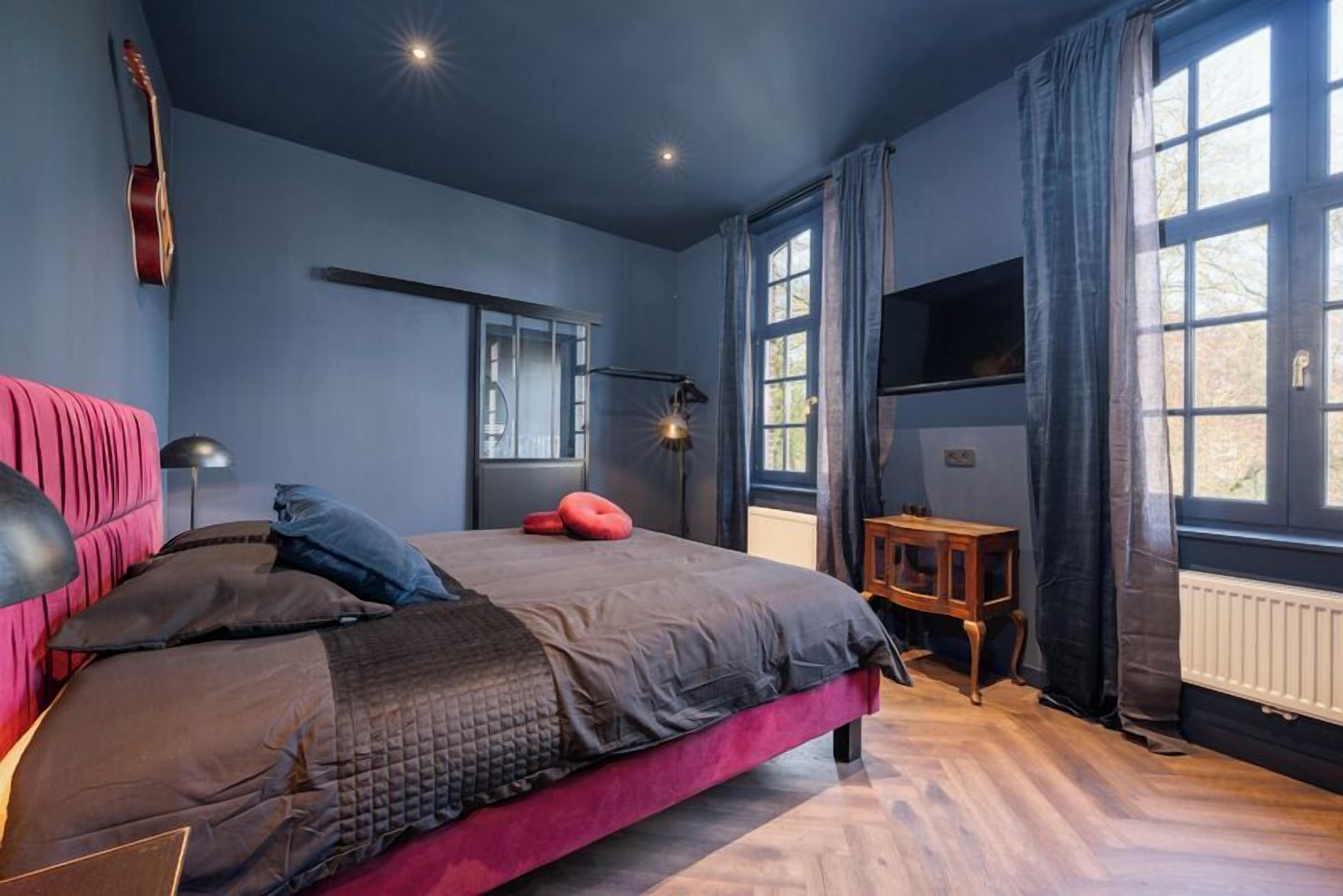 Ein Schlafzimmer mit Bett, Gitarre, Schreibtisch und Fenster.