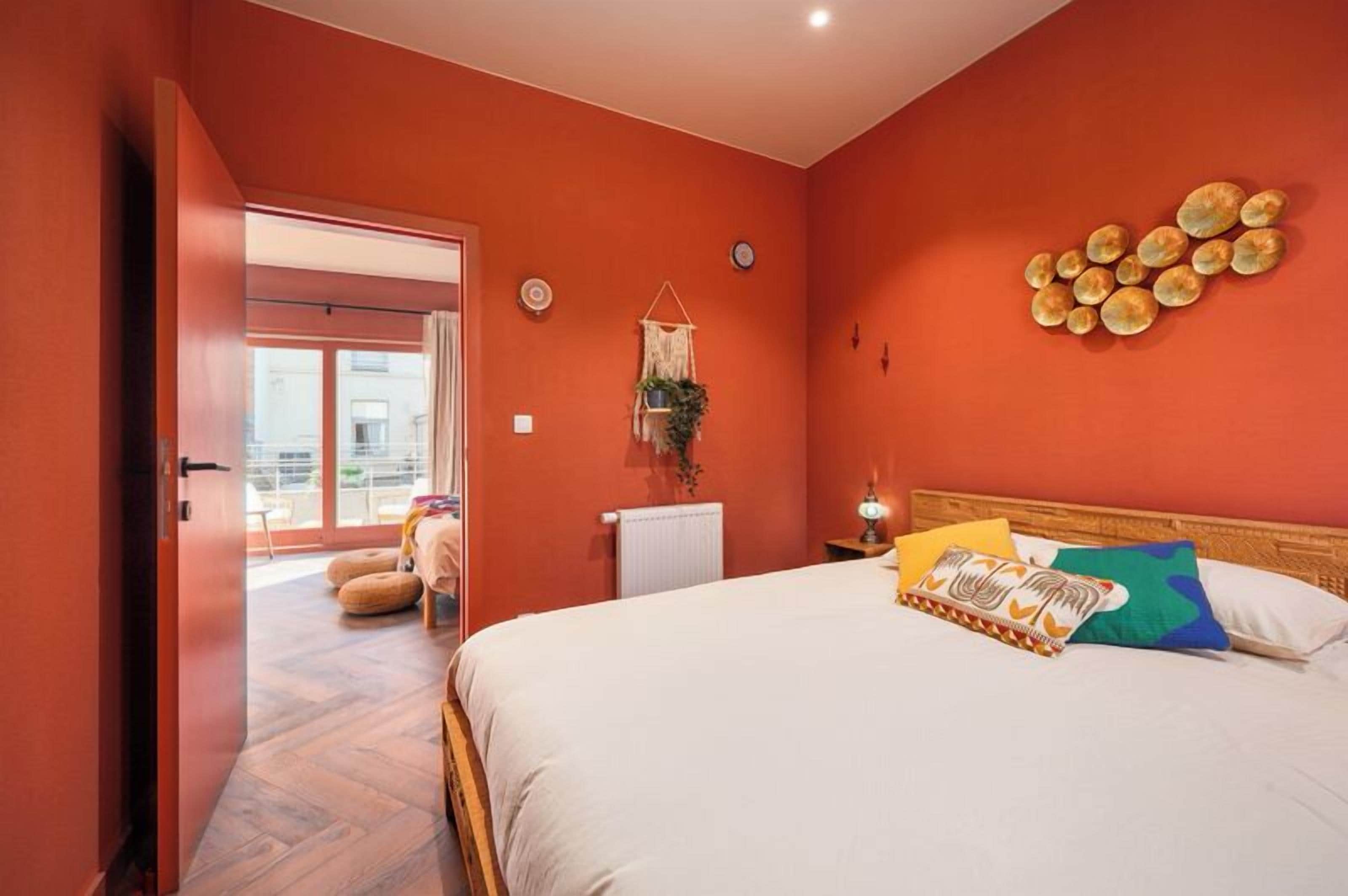 Ein Schlafzimmer mit Bett, Fenster, Tür, einer Wanduhr und einer Wanddekoration.