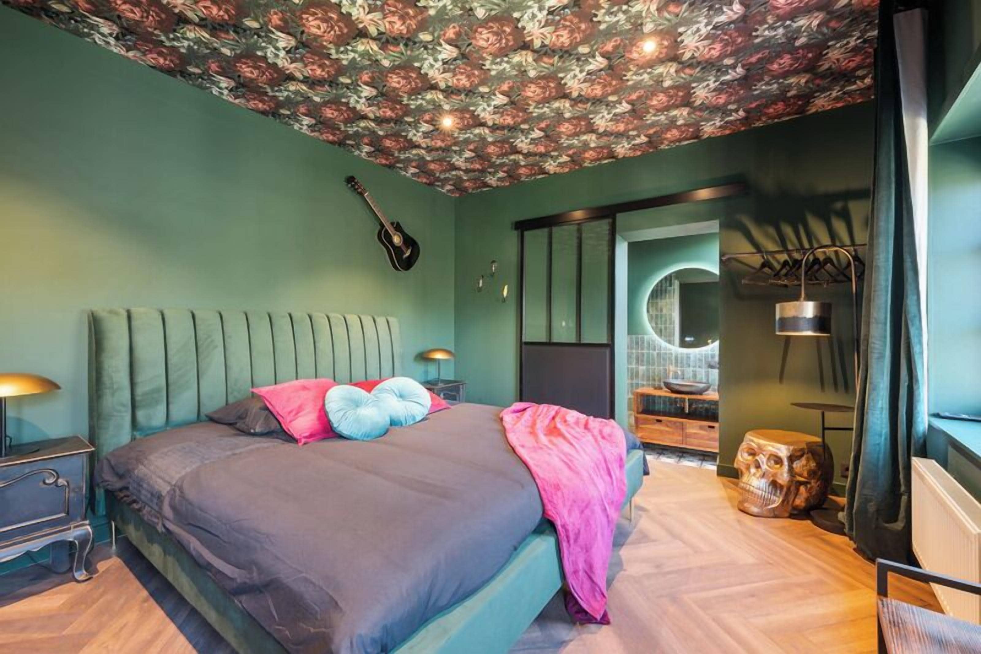 Une chambre à coucher avec un lit, une guitare, un miroir et un décor représentant un crâne.