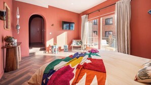 Une chambre avec un grand lit, une télévision et une vue sur l’extérieur.