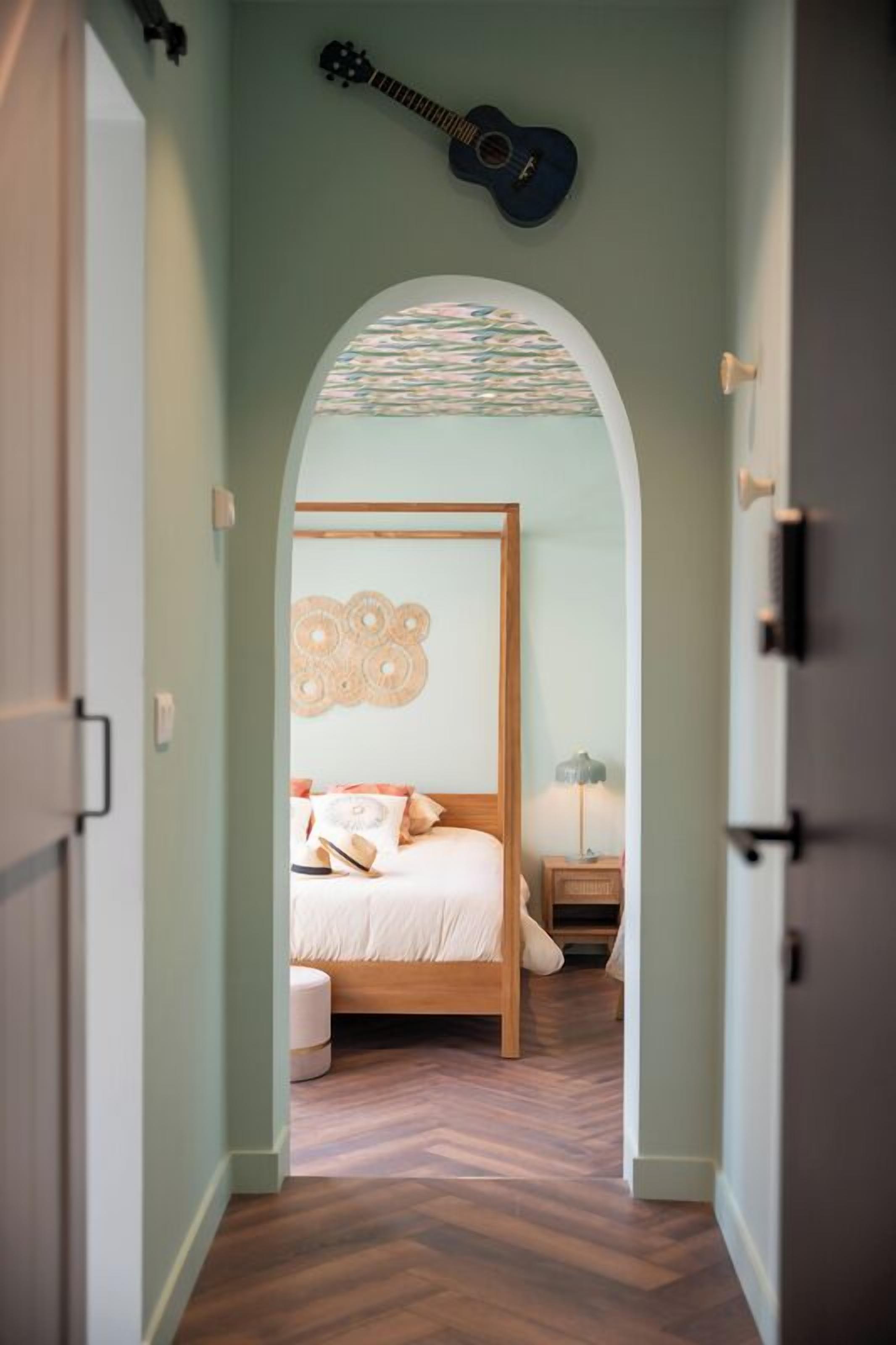 Une chambre à coucher avec un lit, une guitare et un élément décoratif mural.
