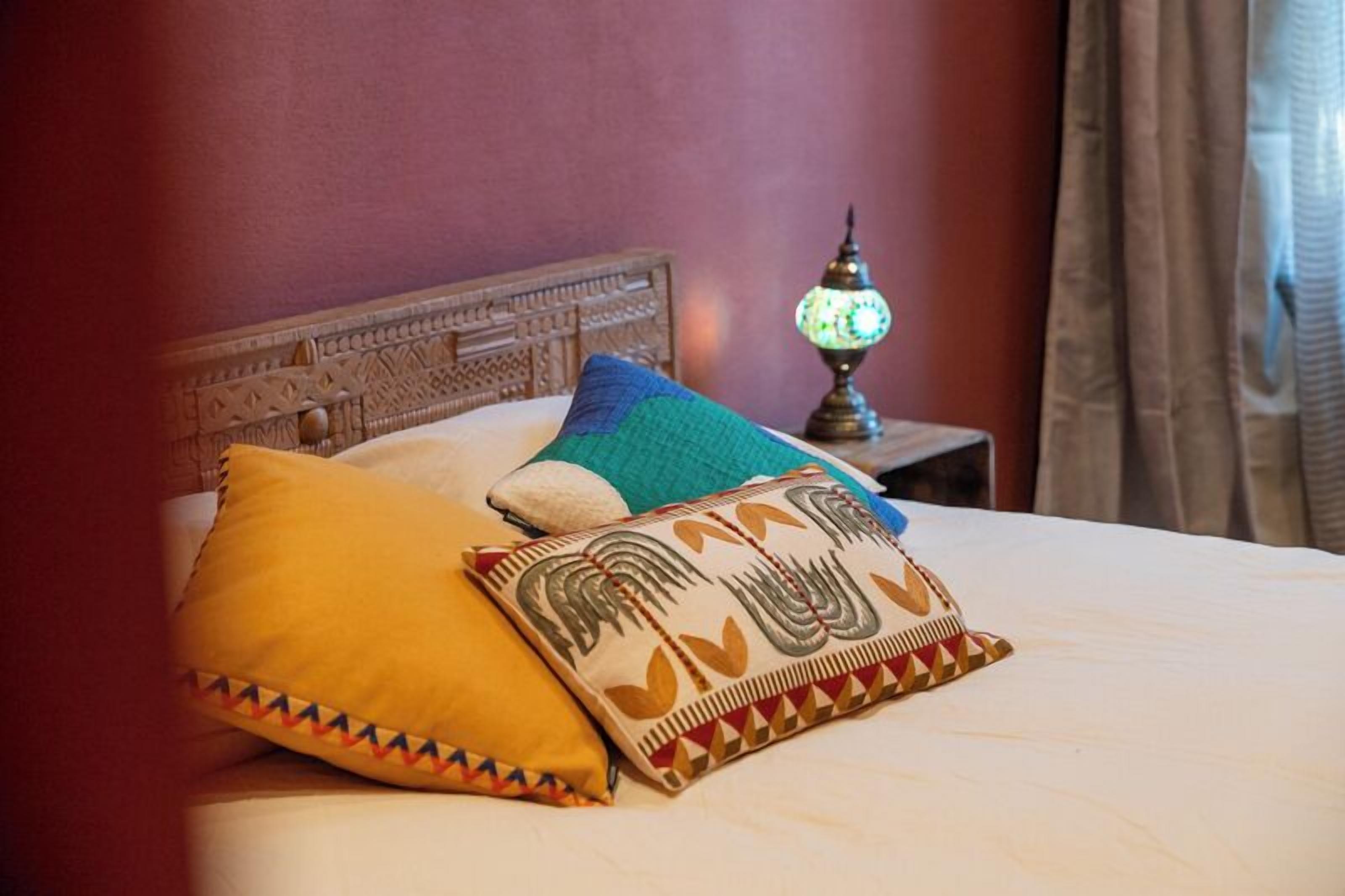 A bed with decorative pillows and a nightstand with a lamp.