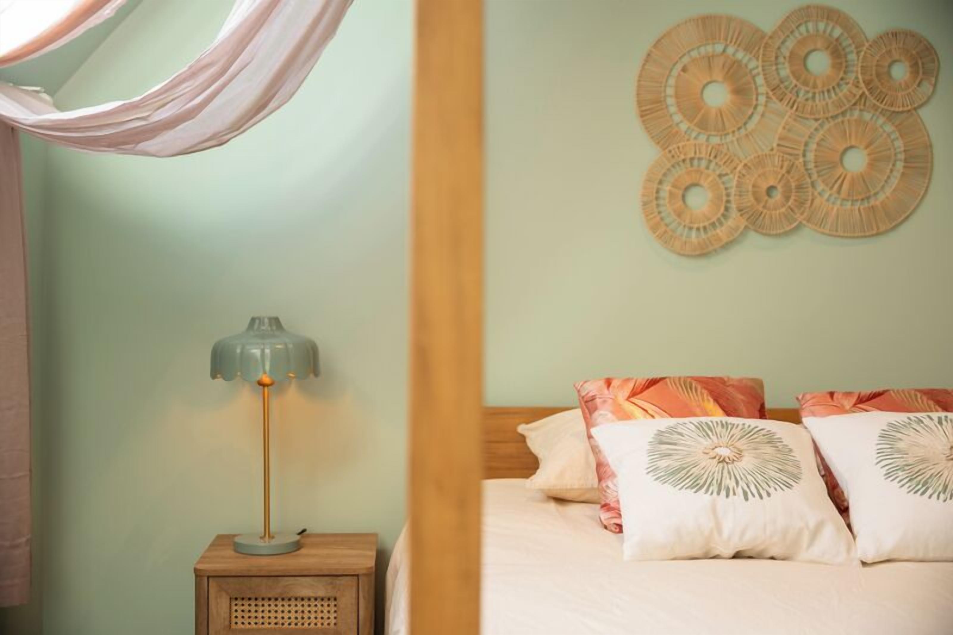 A bedroom with a bed, a bedside lamp, and wall decor.
