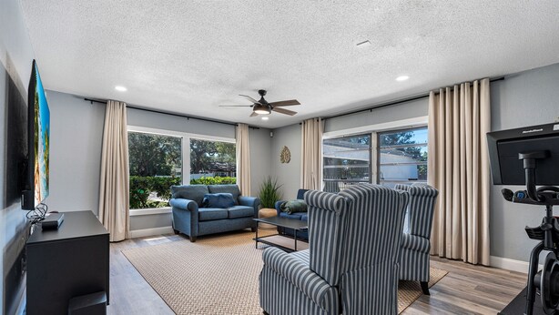 A modern living room with a sofa, armchair, TV, and exercise bike.