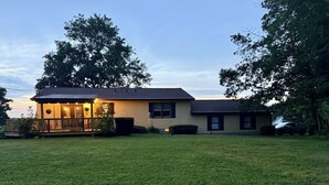 A two-story house with a porch and a well-maintained lawn. - Secluded, elegant country home only 10 minutes from Downtown Ithaca! (Ithaca)