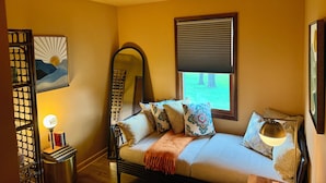 A cozy room with a bed, a standing lamp, a bookshelf, and a window with blinds. - Secluded, elegant country home only 10 minutes from Downtown Ithaca! (Ithaca)