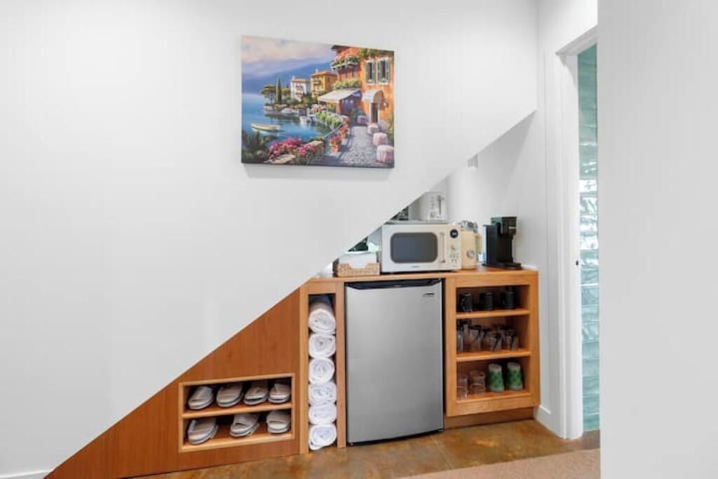 Une cuisine compacte équipée d’un réfrigérateur, d’un four à micro-ondes et d’étagères en bois.