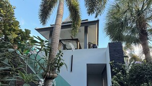 Ein modernes Haus mit zwei Etagen und einer gläsernen Treppe, die zu der oberen Etage führt.