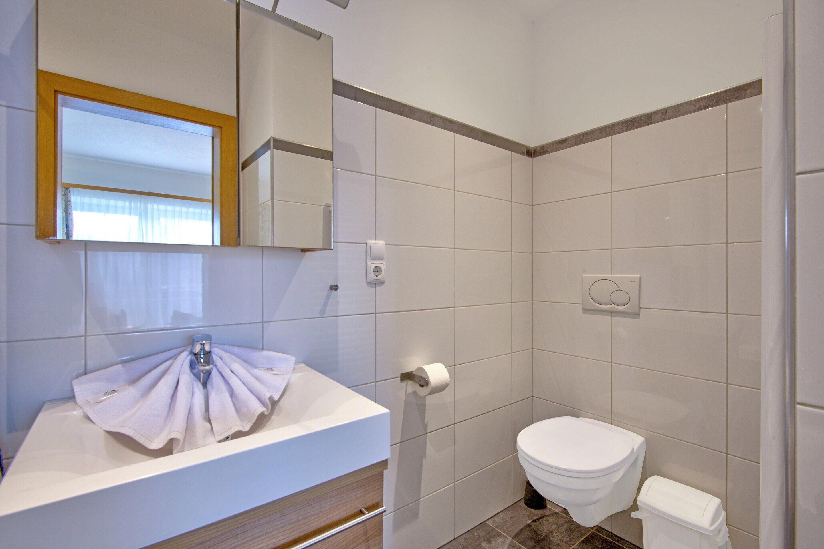 A bathroom with a white sink, mirror, and toilet.