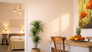 A room with a bed, a dining table with chairs, a potted plant, and a fruit bowl. - Masseria Luci Grande (Scorrano)