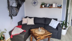A living room with a grey sofa, a wooden coffee table, a bookshelf, and a wall-mounted compass. - Cozy vacation apartment in central Norway with mountains and sea on your doorstep (Trøndelag)
