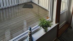 A wooden deck with a railing, a potted plant, and a decorative wind chime. - Cozy vacation apartment in central Norway with mountains and sea on your doorstep (Tr øndelag)