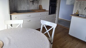 A compact kitchen with white cabinets, a wooden countertop, and a dining area with a round table and white chairs. - Cozy vacation apartment in central Norway with mountains and sea on your doorstep (Trøndelag)