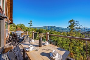 Un espace extérieur aménagé pour les repas, avec une table pour deux, un barbecue et une vue imprenable sur les montagnes.